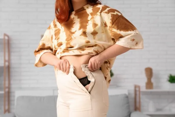 Image of woman trying to do her trousers up after pregnancy weight gain Sheffield